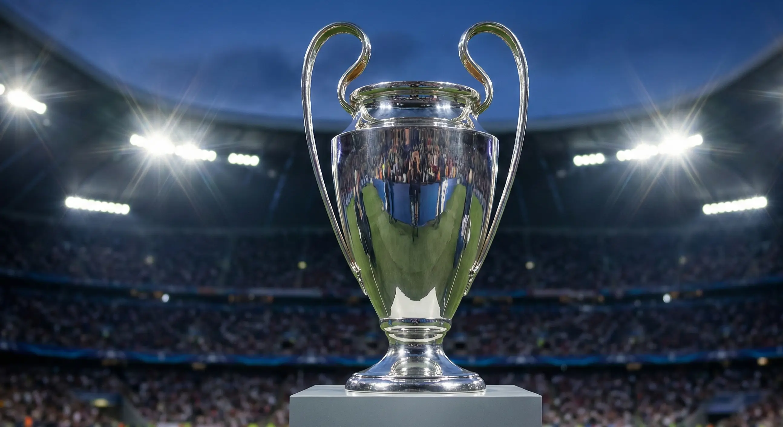 Champions League trophy on display with stadium lights in background