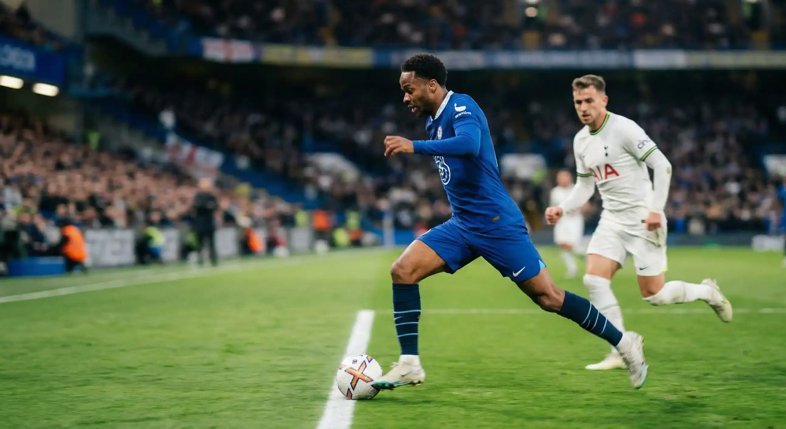Football winger sprinting with the ball down the sideline during a match